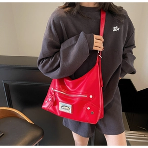 Detail view of red faux leather tote bag with silver metal studs and zipper pocket