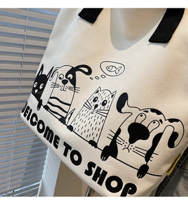 Détail du sac cabas en toile blanche avec motifs de dessins animés et anses tissées noires