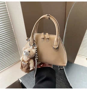 Close-up of beige leather bowling bag with cute teddy bear charm and double handles