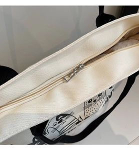 Détail de la fermeture éclair argentée et de l'imprimé chat sur le sac fourre-tout en toile
