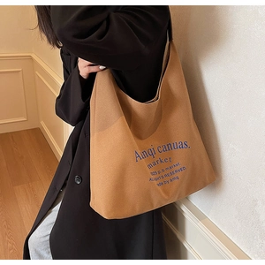 Détail d'un grand sac cabas en toile marron avec lettrage bleu dans un cadre intérieur