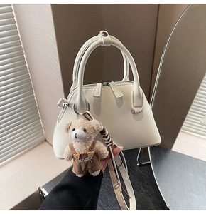 Cream bowling handbag with plush bear charm and long shoulder strap in soft light