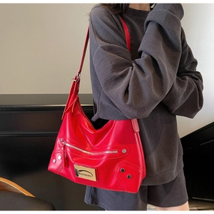 Close-up of a bright red leather tote bag with silver zippers and rivet details