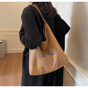 Détail du sac cabas en toile kaki avec lettrage bleu porté à l'épaule