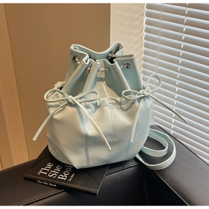 Detailed view of light blue leather bucket bag with bow tie and silver chain drawstring