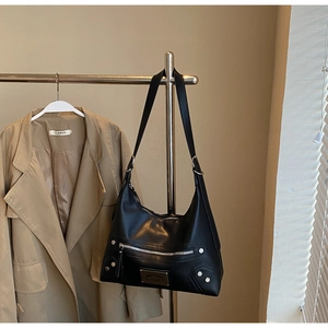 Detail of black leather tote bag featuring silver rivet hardware and external zipper pocket