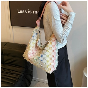 Detail of colorful woven checkerboard tote bag with fringe edges and pink leather handles