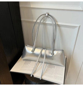 Detail of silver metallic baguette bag with long leather pullers on open vintage books