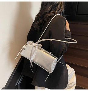 Silver metallic shoulder bag with white lace bow detail worn by model on stairs
