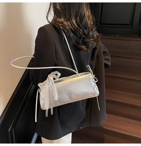Detail of silver shoulder bag featuring delicate white lace trim and bow knot decoration