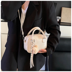 Creamy leather pillow bag with plush bear charm and textured rope detail