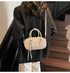 Modèle portant un sac bowling beige à texture froissée et logo UOR UOR sur des escaliers