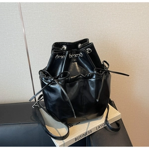 Detail of black bucket backpack with silver chain, drawstring closure and bow accents