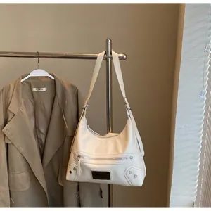 Close-up of beige leather hobo bag featuring silver rivets and metal zipper details
