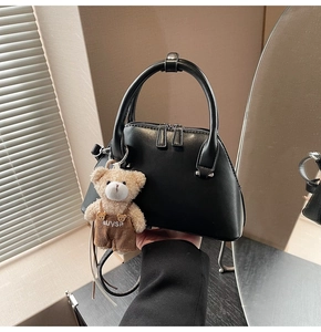 Detail of black Boston bag with a cute teddy bear charm and adjustable shoulder strap
