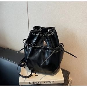 Close-up of black leather bucket backpack with silver chain drawstring and bow detail