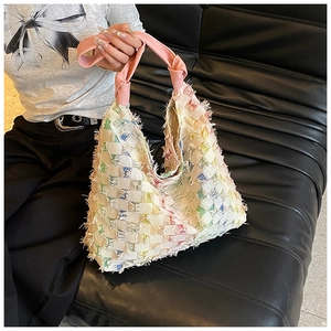 Close-up of a colorful checkered woven tote bag with fringe edges and leather handles