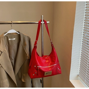 Detail of red leather tote bag showing Noronoro silver logo plate and rivet decoration