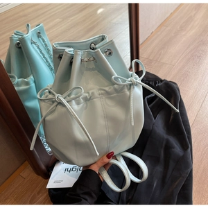 Detail view of light blue bucket backpack with drawstring closure and bow accents