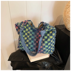 Detail of multi-color distressed denim tote bag with frayed edges on white book