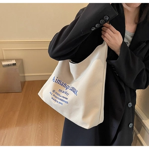 Détail du sac cabas minimaliste en toile blanc cassé avec texte graphique bleu stylé