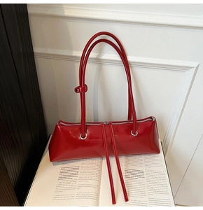 Detail of red patent leather baguette bag with silver double zippers on a fashion magazine
