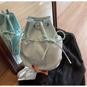 Detail of light blue bucket backpack with bow decoration and silver hardware finish