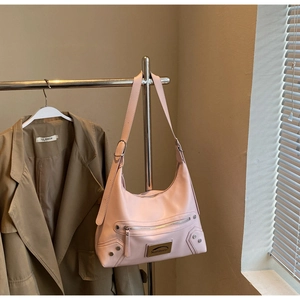 Detail of pink faux leather half-moon shoulder bag with metal studs and zippers