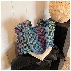 Close-up of colorful checkered woven tote bag featuring frayed edges and denim knotted handles