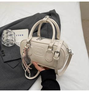Détail du sac bowling crème avec gaufrage UOR UOR et bijou de sac tissé sur veste
