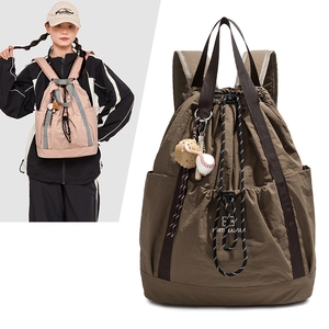 Dettaglio di grande zaino in nylon con coulisse e ciondolo da baseball su un modello