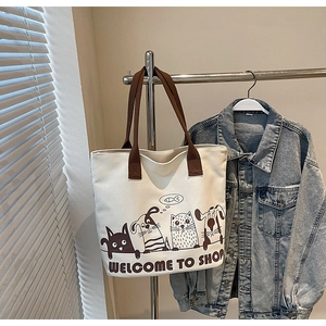 Gros plan sur un sac cabas en toile blanc cassé avec anses brunes et motif animalier