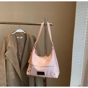 Detail of light pink hobo tote bag with silver studs and metal zipper on textured leather