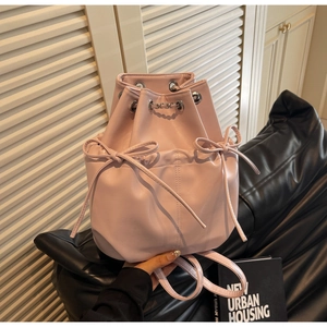 Detail shot of a pink bucket bag with bow drawstrings and silver metal chain accents