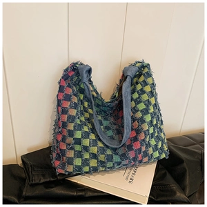 Detail of colorful checkerboard tote bag with fringe edges on white books