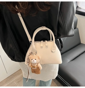 Detail of cream bowling handbag with cute bear charm and adjustable shoulder strap