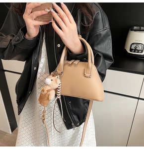 Detail of khaki bowling shell bag with bear pendant and adjustable crossbody strap