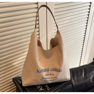 Gros plan d'un sac cabas en toile beige avec logo bleu sur un fauteuil en cuir