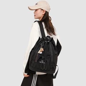 Dettaglio dello zaino in nylon nero con ciondolo da baseball indossato da una modella