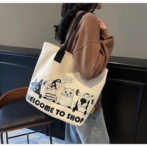 Détail d'un sac cabas en toile beige montrant sa grande capacité et son motif chat