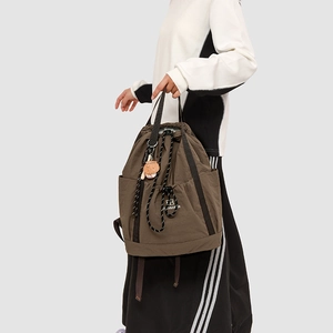 Dettaglio dello zaino in nylon marrone scuro con chiusura a coulisse e ciondolo orso