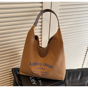 Détail d'un sac cabas marron en toile avec imprimé bleu et bandoulière en cuir