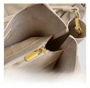 Gros plan sur la fermeture éclair en métal doré de ce sac seau beige sophistiqué