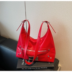 Detail of red leather tote bag showing silver zippers and metallic stud accents