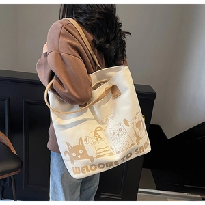 Détail d'un grand sac cabas en toile crème avec imprimés animaux et anses marrons