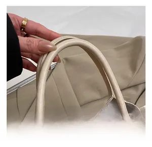 Détail du sac à main en cuir beige avec finitions dorées et poignée en corde tressée