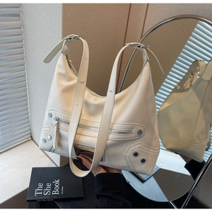 Close-up of off-white tote bag featuring silver studs, zippers and branded metal plate