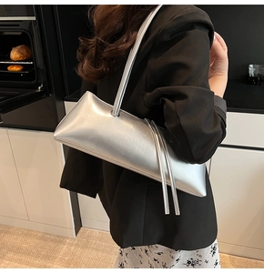 Silver baguette shoulder bag with metallic texture and sleek tassel detail worn by model