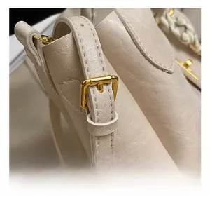 Détail de la bandoulière réglable avec boucle dorée sur un sac seau beige texturé