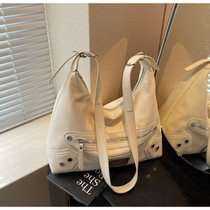 Close-up of off-white faux leather tote with silver rivets and motorcycle style zippers